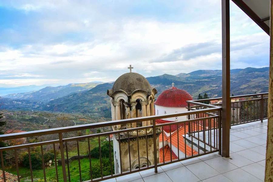 Το μπαλκόνι με θέα στο καμπαναριό, τα κόκκινα τρούλα και τα βουνά